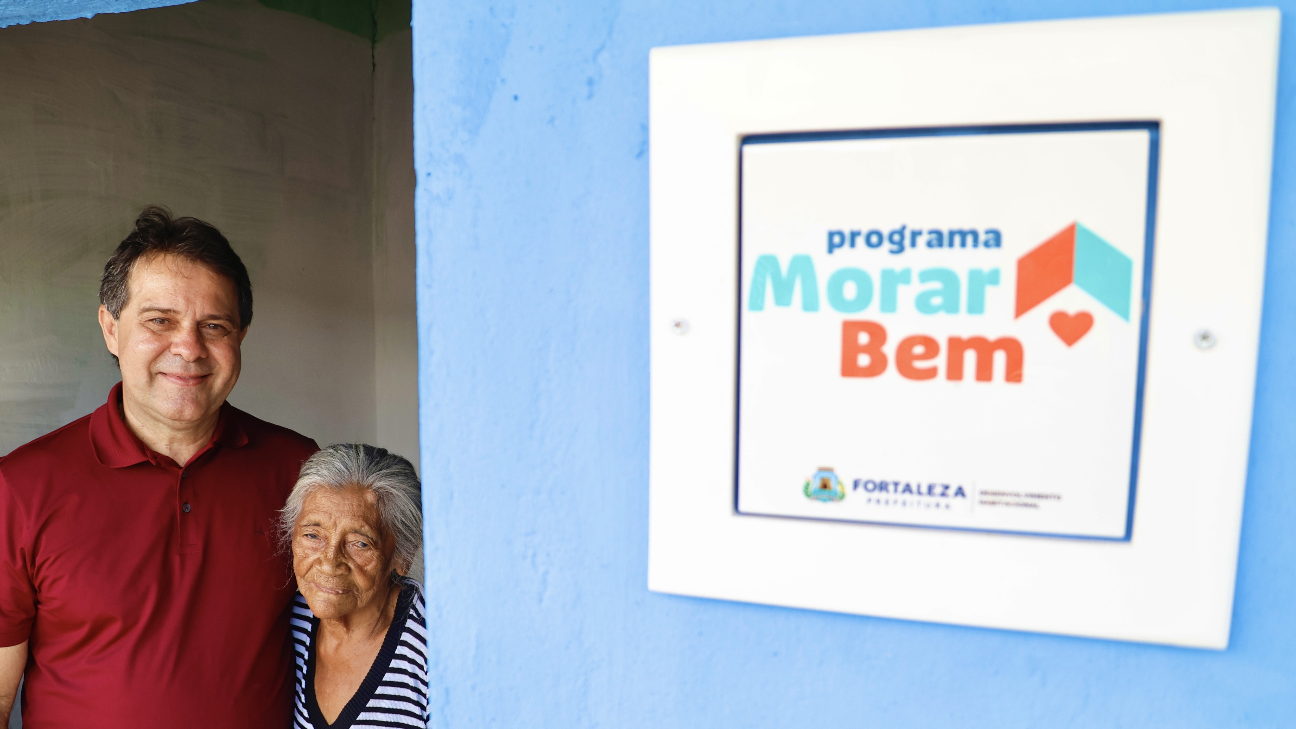 prefeito evandro e uma senhora na janela de uma casa